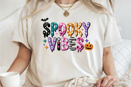 Person wearing a white t-shirt with 'Spooky Vibes' text and Halloween graphics.