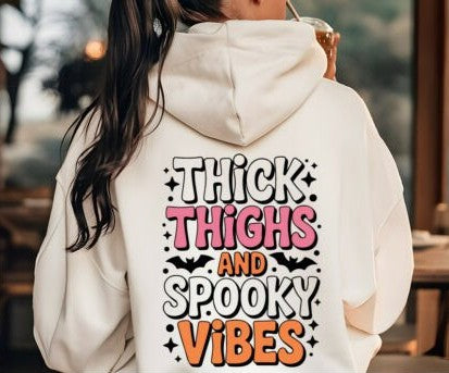 Person wearing a hoodie with 'Thick Thighs and Spooky Vibes' text on the back.