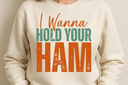 Beige sweatshirt with colorful text 'I Wanna Hold Your Ham' on a plain background
